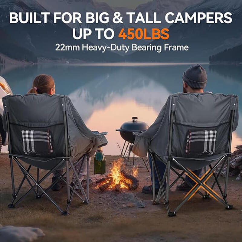 Two oversized dark gray folding camping chairs with plaid side pockets, designed for big and tall campers, supporting up to 450 lbs with 22mm heavy-duty bearing frames, shown at a lakeside campsite with a campfire, grill, and mountain sunset backdrop