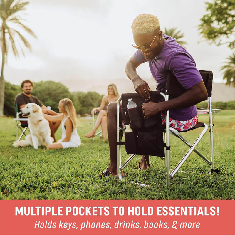 Man on grass using a folding director's chair with multiple pockets to show storage functionality (for keys, phone, drinks, books, etc.