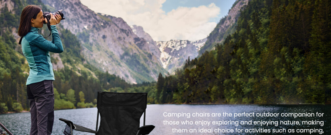 A forested lakeside landscape scene with a black portable folding camping chair placed on the grass, next to which an outdoor female photographer is capturing photos. The emphasizes that the camping chair is the perfect outdoor companion for nature exploration, suitable for camping, hiking, and outdoor photography activities.