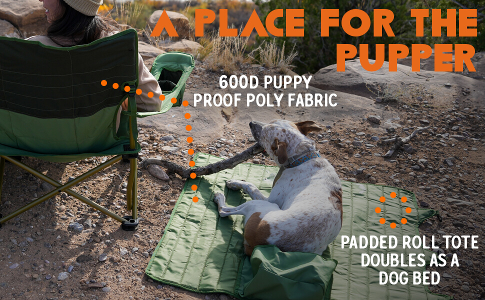 A spotted dog lies on a green padded roll-up tote that doubles as a dog bed, chewing a stick in a rocky outdoor campsite. A person sits in a matching green camping chair nearby. Orange text at the top reads "A PLACE FOR THE PUPPER". White text annotations highlight features: "600D PUPPY PROOF POLY FABRIC" and "PADDED ROLL TOTE DOUBLES AS A DOG BED